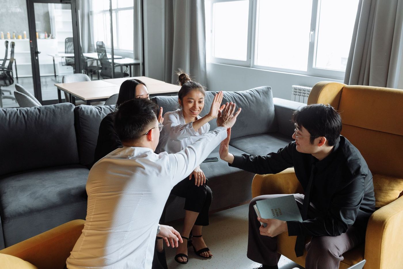 华人企业团队在明亮的现代办公室里击掌庆祝 · A Chinese-American business team celebrating in a bright modern office